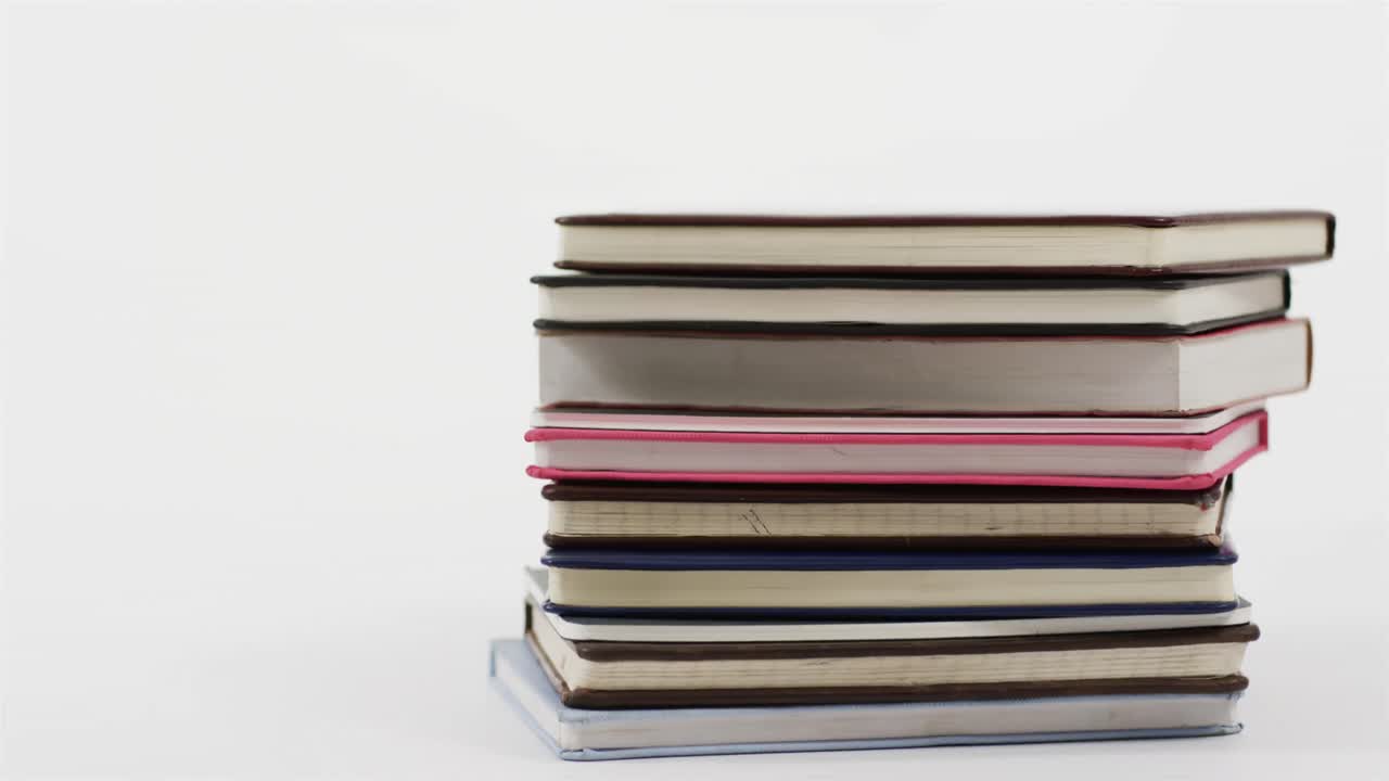 Close up of stack of books on white background, in slow motion