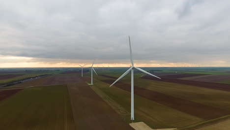 Aerial-back-tracking-over-wind-turbines-in-crop-fields-during-sunset-France