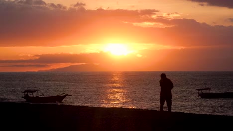 Timorese-person-walking-along-the-ocean-shoreline-on-beach-during-beautiful-golden-sunset-in-Dili,-Timor-Leste,-Southeast-Asia