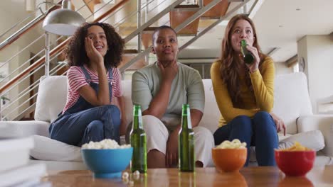 diverse group of female friends having fun drinking beer watching tv at home