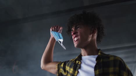 Mixed-race-man-protesting-while-holding-protest-face-mask-in-the-air