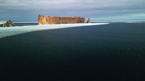 aerial view of percé rock in the winter with ice on the ocean