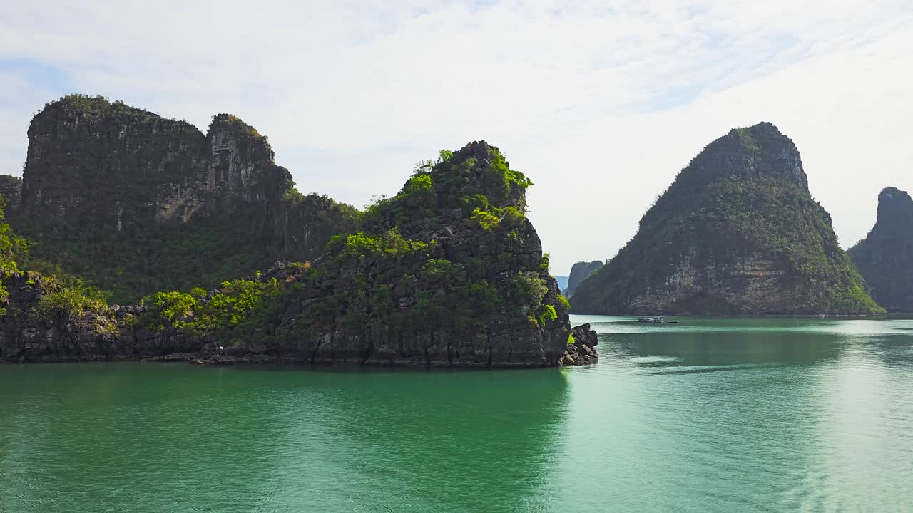 Towering limestone karsts emerge dramatically from the emerald waters of Ha Long Bay, creating mesmerizing seascape where ancient rock formations stand as silent sentinels in Vietnam's natural wonder