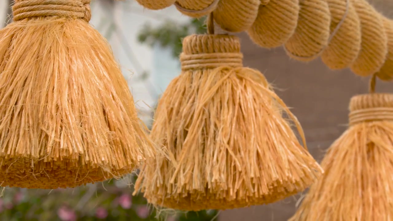 Primo piano di una spessa corda di paglia con nappe appesa a un torii di pietra.