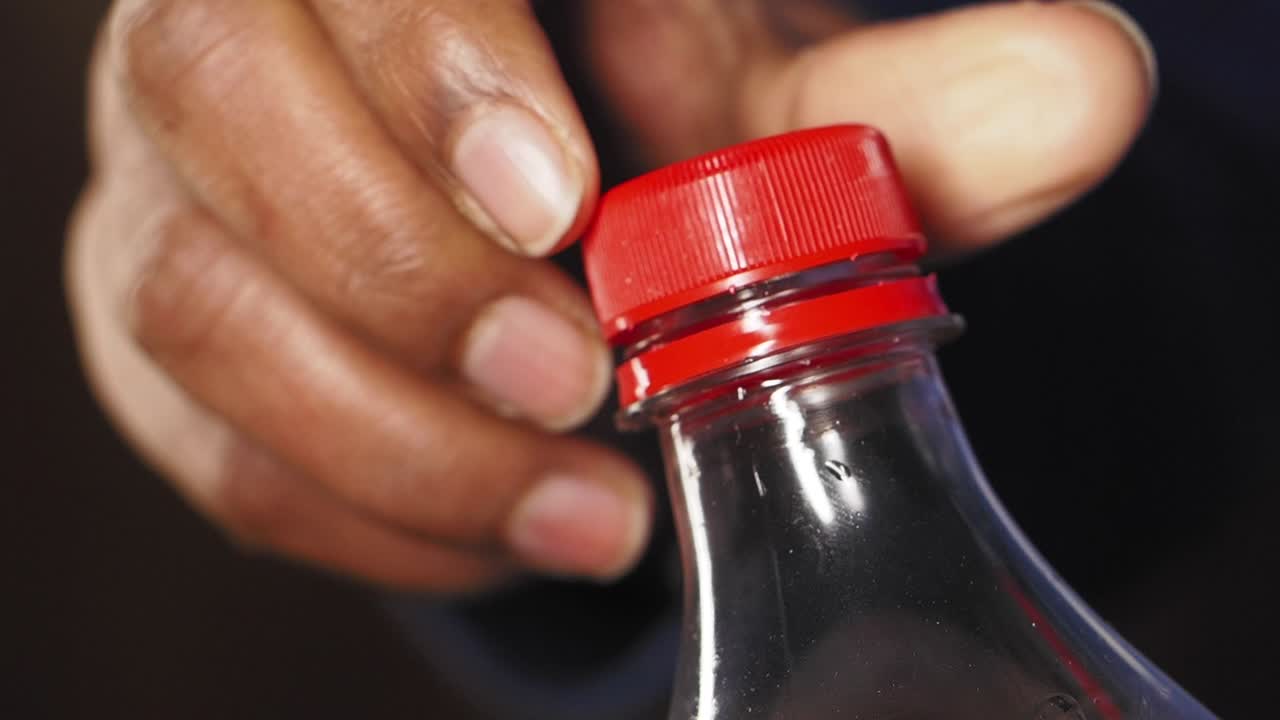 Hand opening a soda bottle
