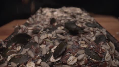 Slow-motion-macro-shot-of-seeds-being-dropped-on-top-of-freshly-baked-bread