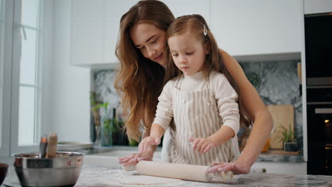 adorable mom daughter kneading dough with pin close up. woman bonding to child