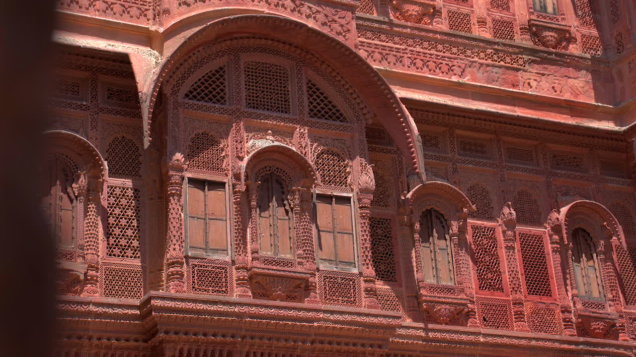 Un primo piano statico della squisita lavorazione a traforo in pietra e degli archi ornamentali sulla facciata del Forte Mehrangarh, che mostra la tradizionale maestria artigianale Rajput a Jodhpur, Rajasthan, India.