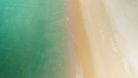 Costa-Y-Olas-Tranquilas-A-Lo-Largo-De-Una-Playa-Tropical-Vacía-Con-Agua-Azul-Clara,-Vibraciones-De-Playa-De-Vacaciones,-Toma-Aérea-Superior