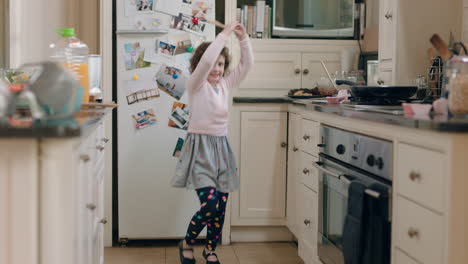 happy little girl dancing in kitchen having fun doing funny dance moves enjoying weekend at home