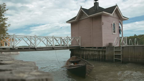 wooden rowing boat next to small beach hut with a dock