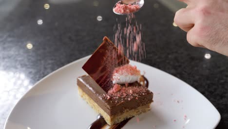 close-up shot of a chef adding the finishing touches and ingredients to his chocolate dessert