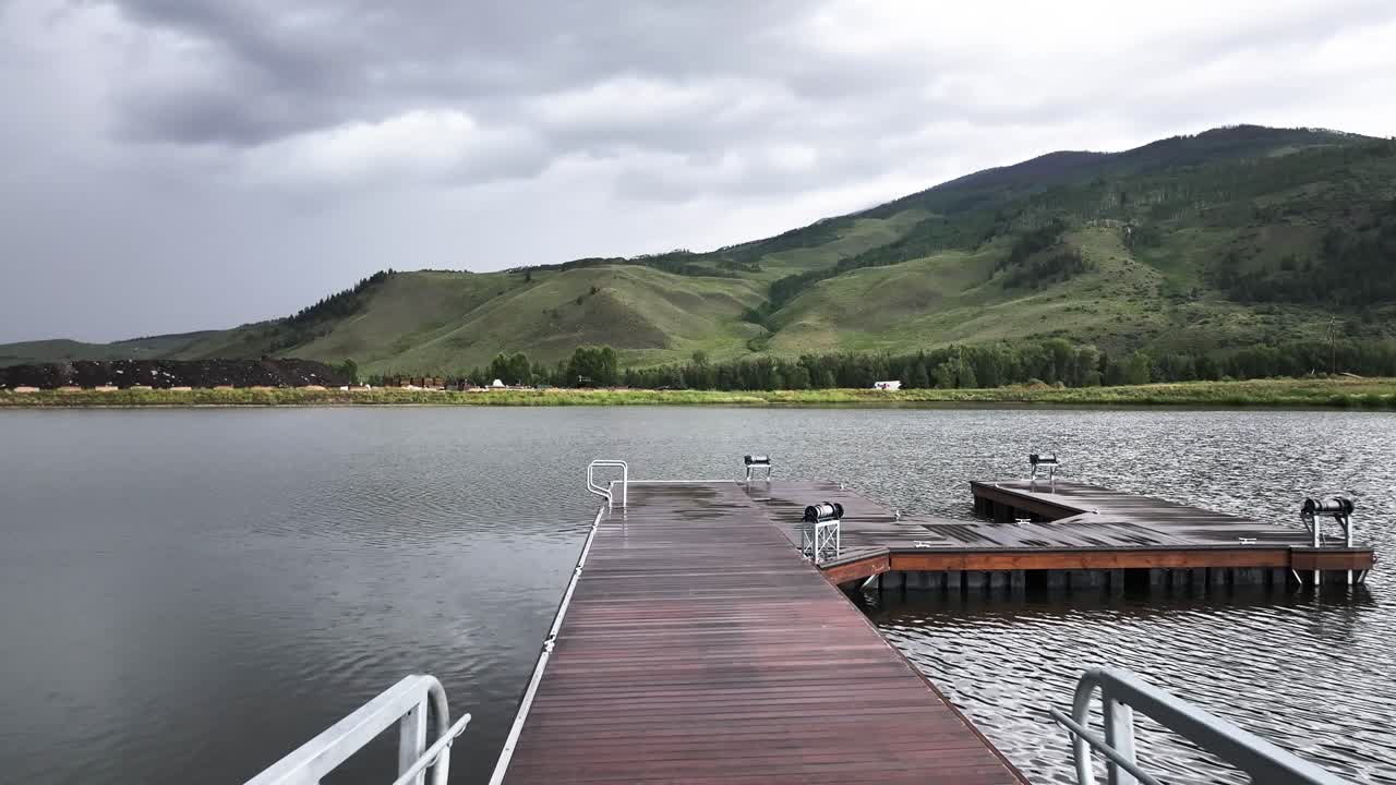 Segnale di attenzione/divieto di accesso e catena che bloccano un pontile per barche in legno su un piccolo lago a Silverthorne, Colorado. Ripresa aerea con dolly.