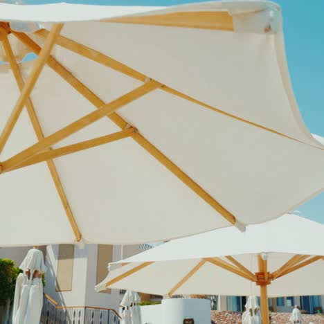 A-Row-Of-White-Umbrellas-Against-The-Blue-Sky-In-A-Luxury-Hotel-1