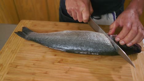 chef cutting into fish in kitchen