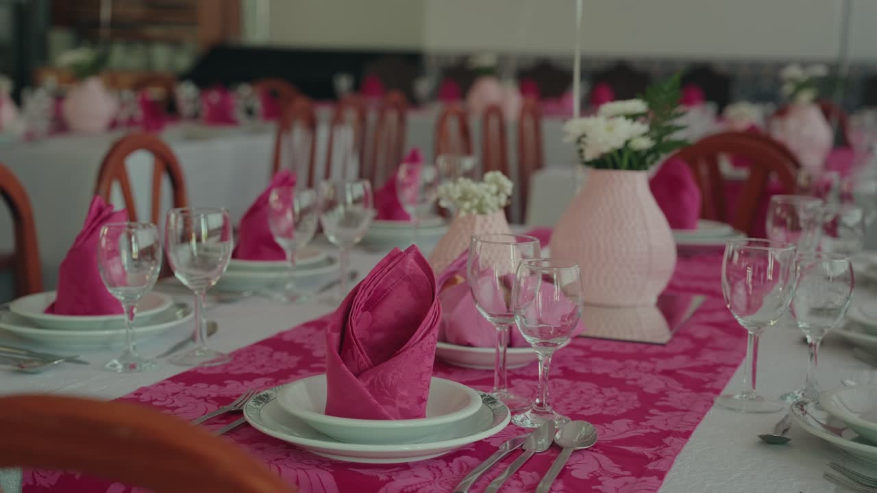 Elegant pink themed table setup with folded napkins and glassware for celebration