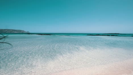 Girl-walking-into-the-turquoise-sea,-knee-deep-and-pink-sand-beach