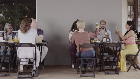 diverse group of friends toasting and socializing at an outdoor restaurant
