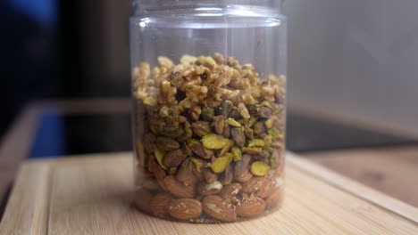 close-up of mixed nuts filling plastic jar. prep for clean healthy diet snacks