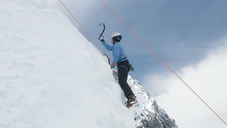 professional male ice climber use gear to ascend icy mountainside, side view