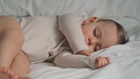 un video de una niña caucásica durmiendo en la cama de su casa.
