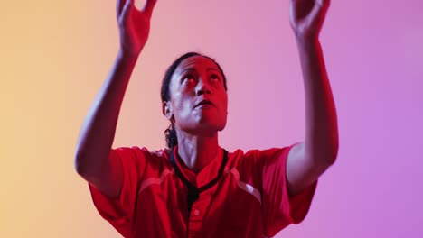 african american female rugby player catching rugby ball over neon pink lighting