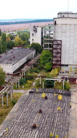 abandoned factory with many ruined buildings. old brick thick pipe on empty plant. deserted industrial territory. aerial view.. vertical video