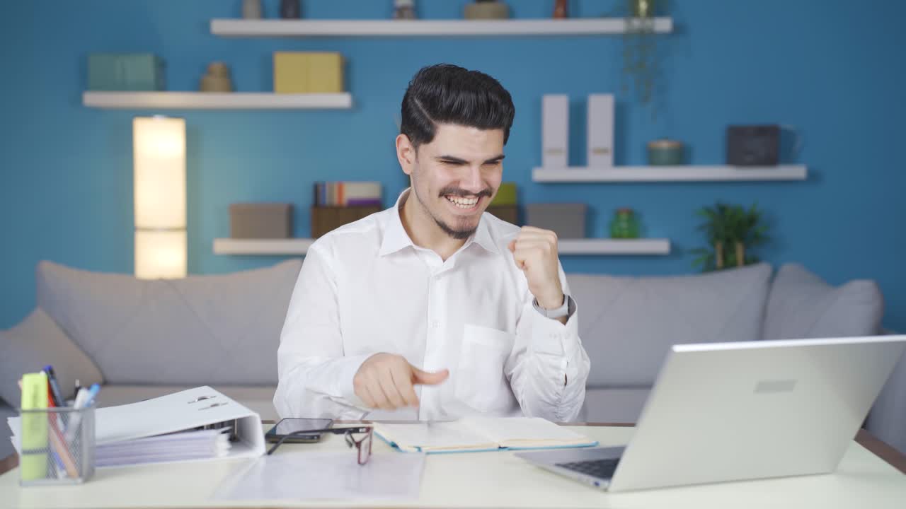 hombre de negocios que trabaja en la oficina de casa regocijándose con buenas noticias.