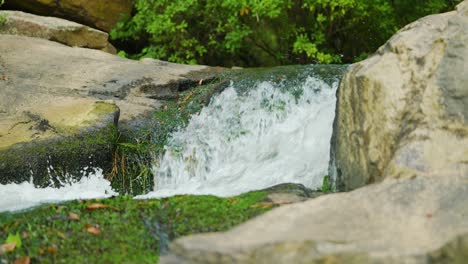 Schöne-Aufnahmen-Eines-Sich-Schnell-Bewegenden-Baches,-Der-Zwischen-Zwei-Felsen-Im-Wald-Schneidet