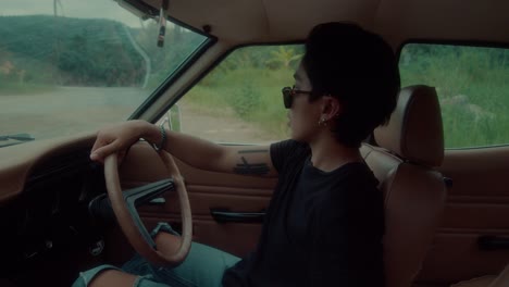 man driving a vintage car on a road trip