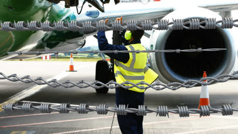 Stacheldraht-Gegen-Flughafen-Mitarbeiter-Mit-Kopfhörern-Arbeiten