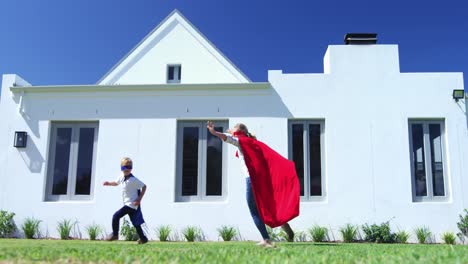 mother and son in superhero costume having fun in garden 4k