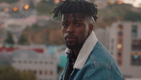 portrait attractive young african american man drinking alcohol enjoying rooftop view of city skyline looking confident at sunset