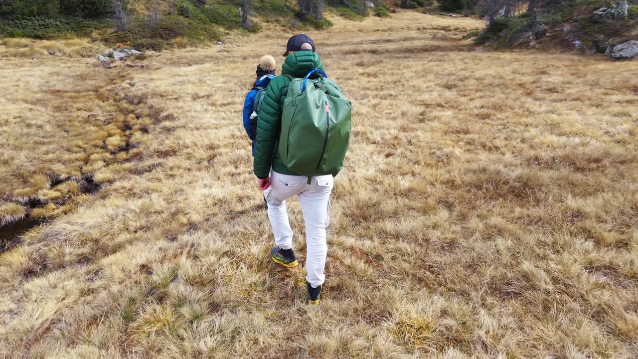 Dağlarda, sırt çantalı bir çift kuru otluk bir alanda yürüyüş yapıyor.
