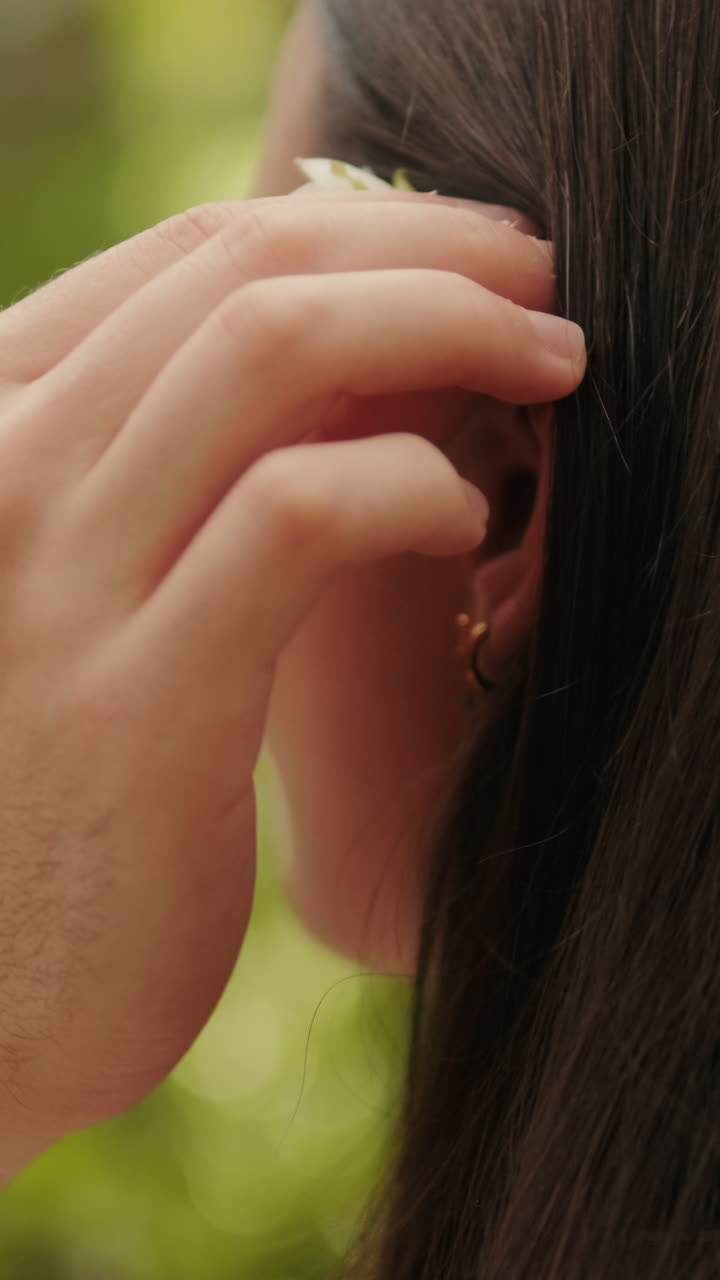 Close up young man putting flower behind his girlfriend's ear