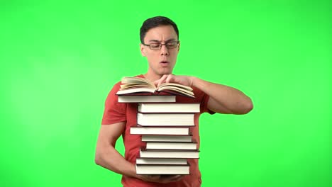 man reading a large stack of books on a green screen