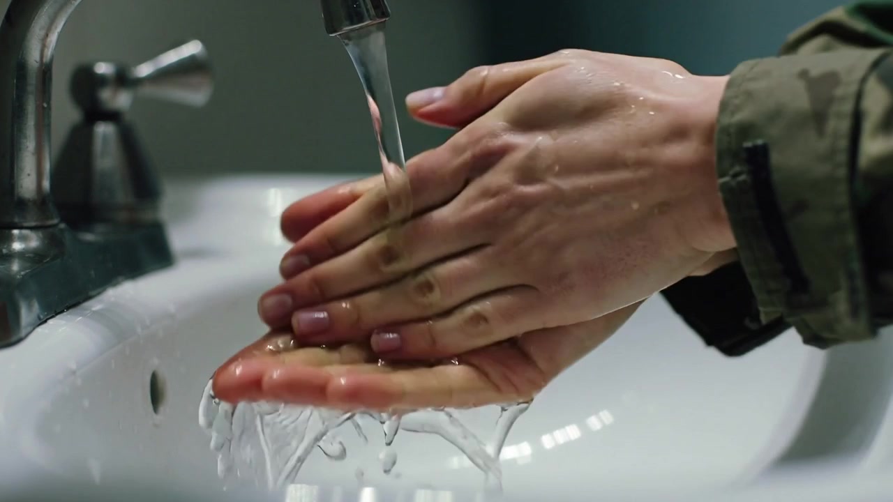Placing adult hands under faucet at restroom sink, rubbing and rinsing, removing dirt, camo sleeve