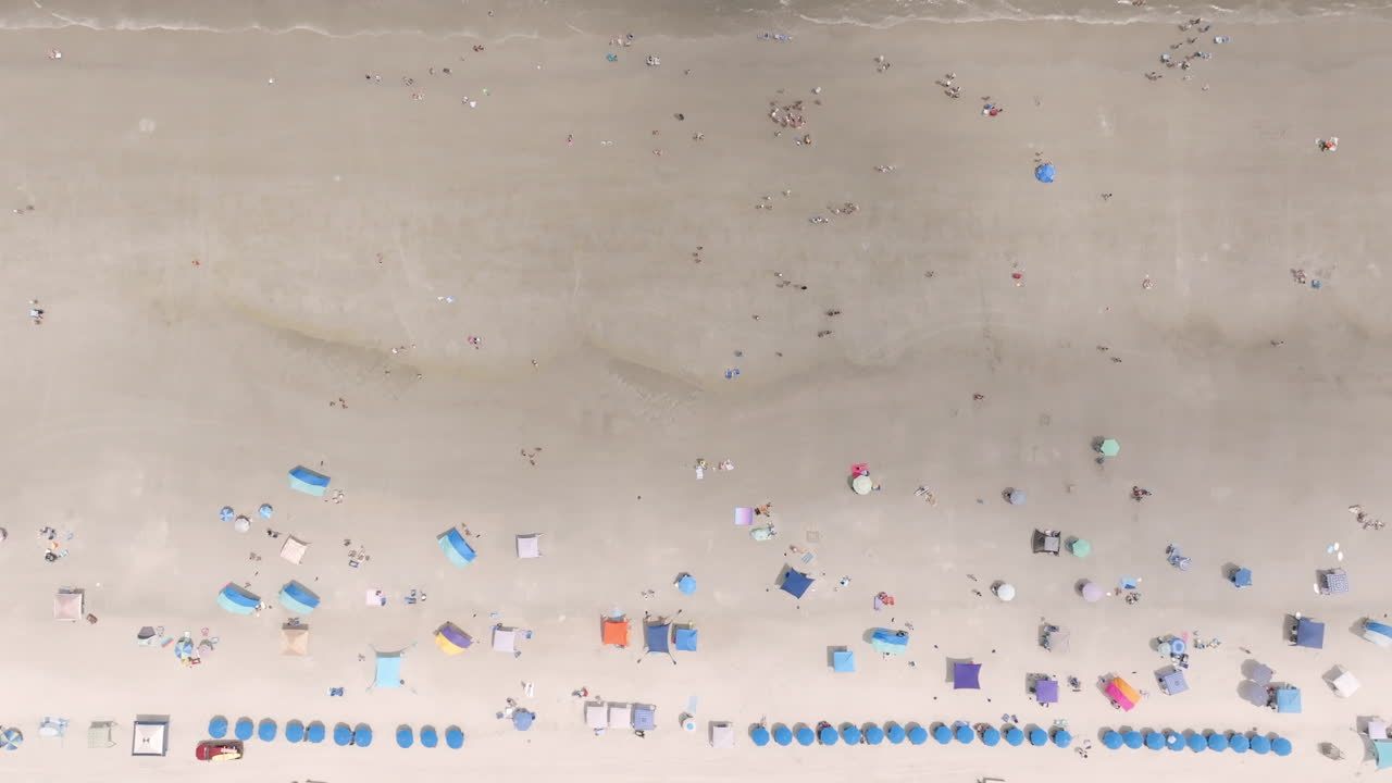 Top-down aerial view of beachgoers and umbrellas arranged in colorful rows along a sandy Hilton Head shoreline