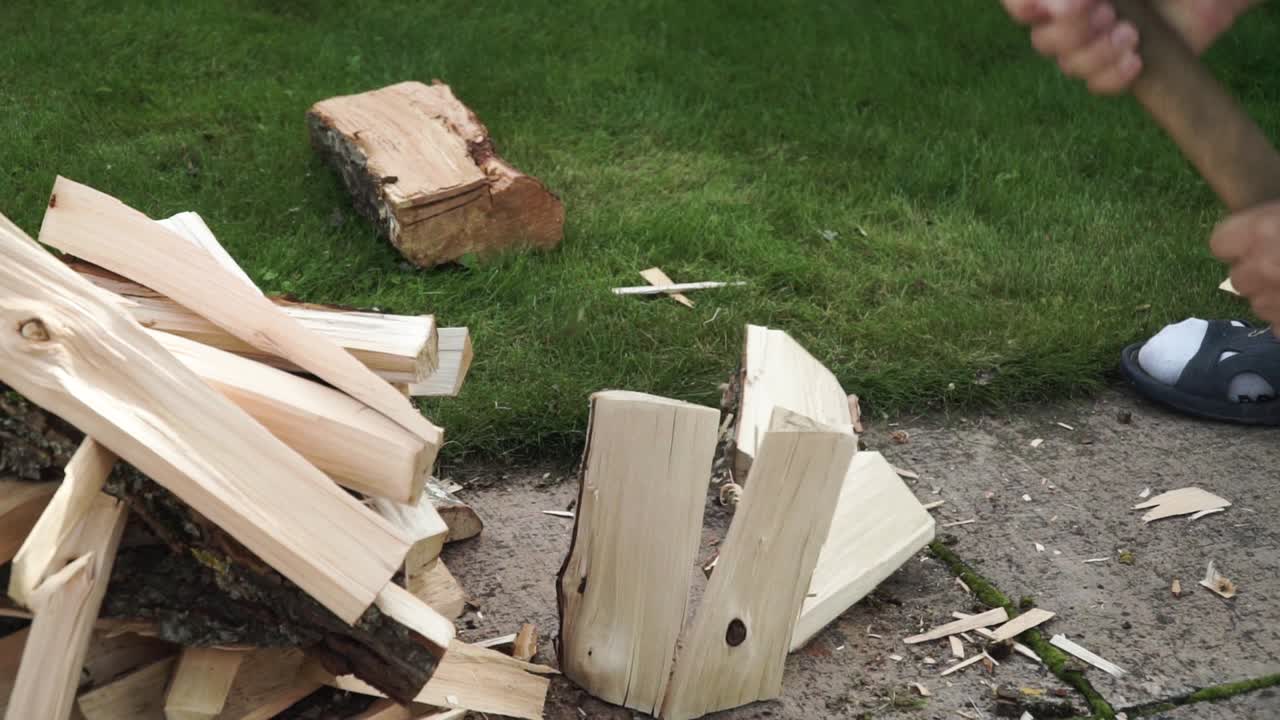 젊은 남자가 나무를 작은 조각으로 자르고 옆에 두고 있다