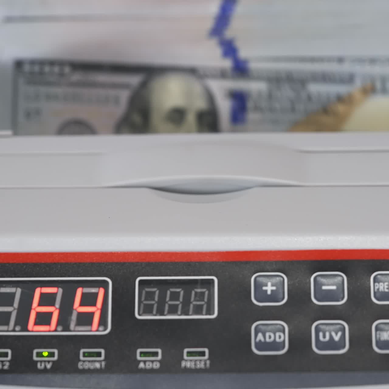 Electronic equipment for counting paper money. Bank worker putting a bundle of one hundred dollar bills into the counting machine for calculation