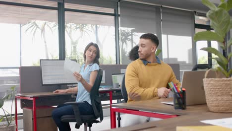 Caucasian-woman-giving-a-document-to-biracial-man-at-office