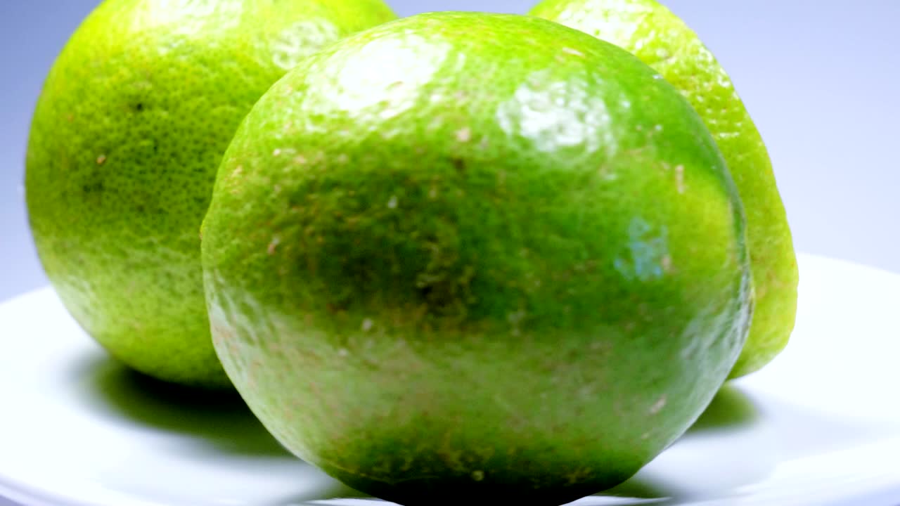 신선한 녹색 레몬 슬라이스는 세부 사항과 함께 스튜디오에서 천천히 회전하고 있습니다.