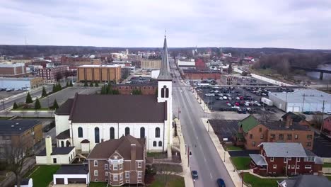 aerial view flyover logansport small white church with steeple in downtown indiana townscape