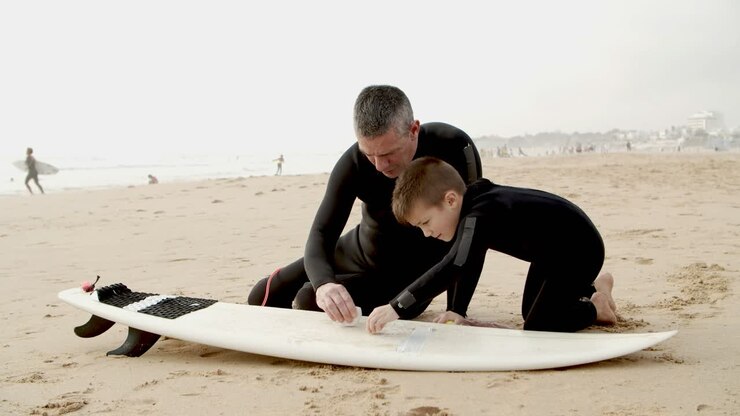 Padre e figlio che cerano la tavola da surf in spiaggia