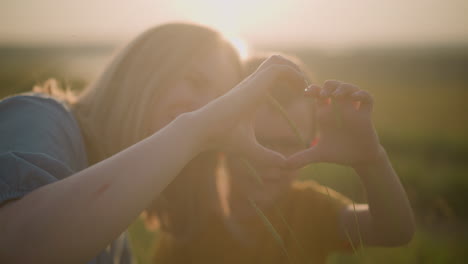 a beautifully blurred image captures the tender moment of a young boy and a woman forming a heart shape with their hands while their heads are joined together