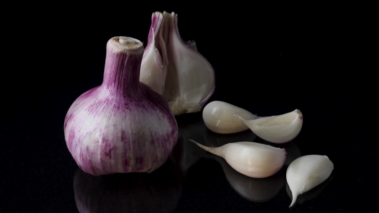 Purple Garlic Bulb and Cloves on Black Background