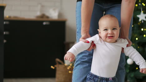 el bebé da sus primeros pasos con la ayuda de la madre