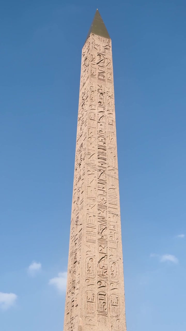 Muinainen hieroglyfeillä koristeltu obeliski seisoo korkeana kirkkaan sinisen taivaan alla Pariisin aukiolla