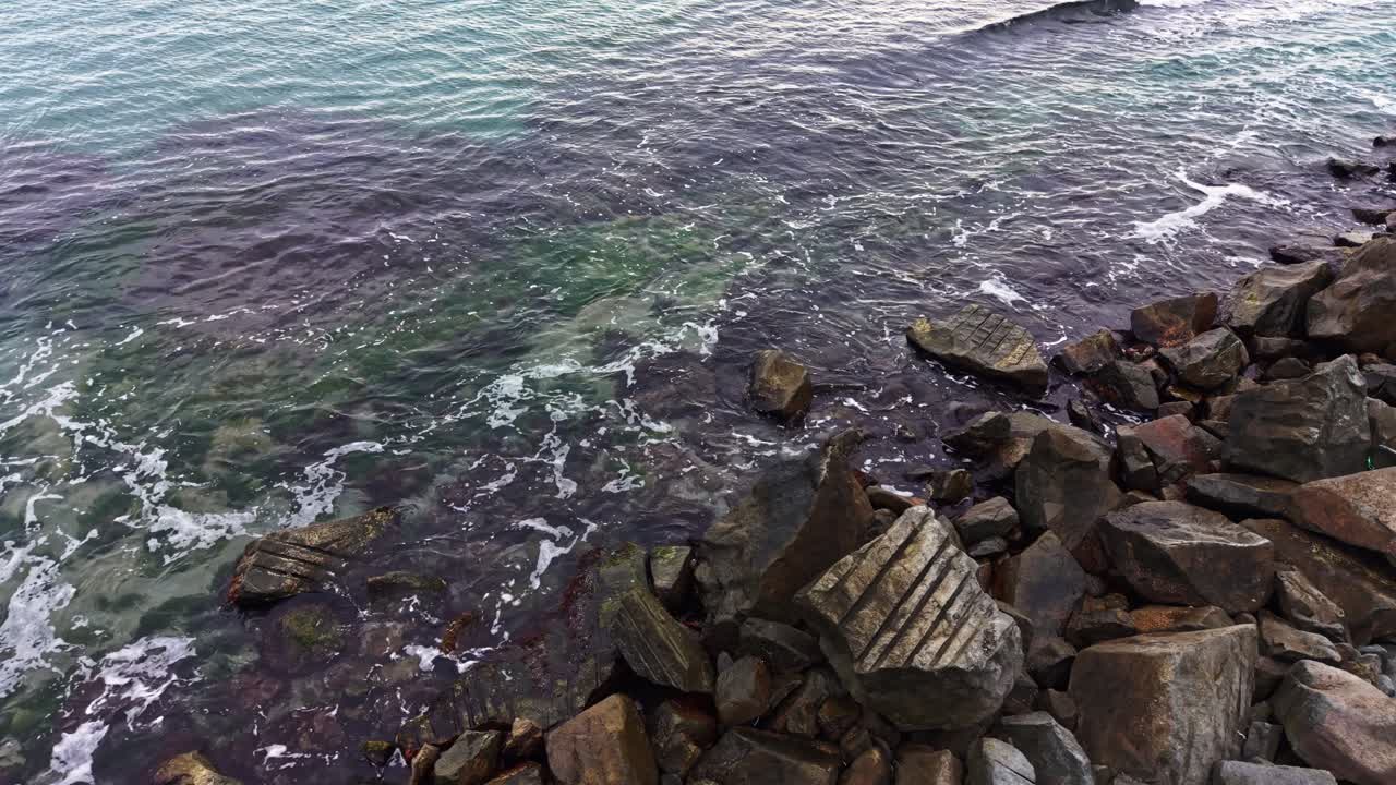 Bølger, der slår ind over en klippekyst ved solnedgang