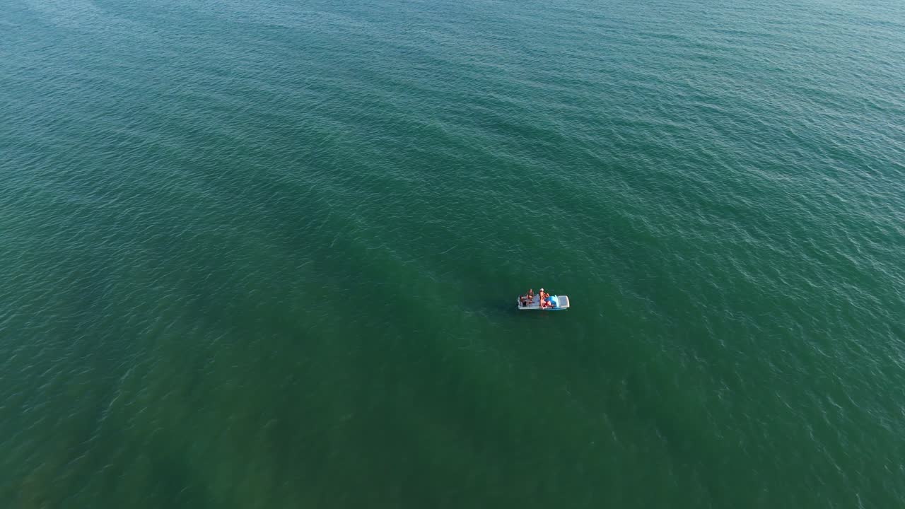멀리 떨어진 해안선 근처의 차분한 파란 물에서 작은 배를 타고 있는 사람들, 공중 사진